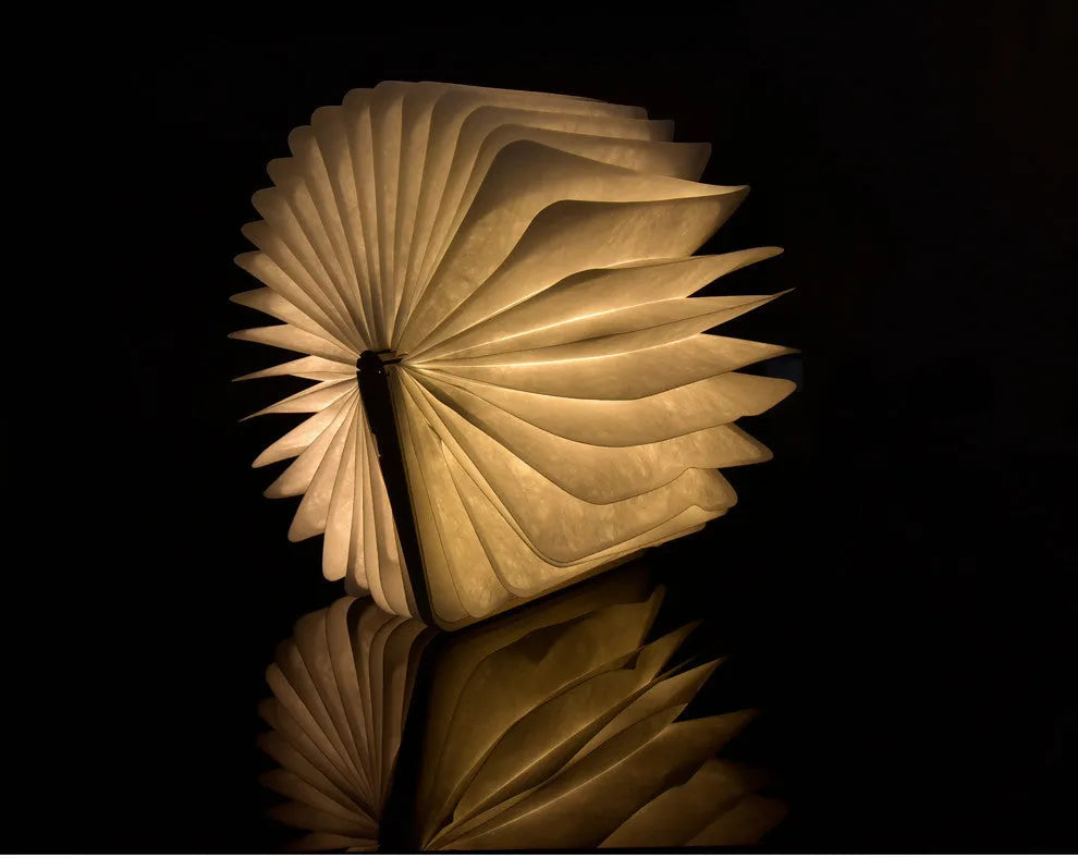Walnut cover LED book light open at an angle showing white light pages on a surface