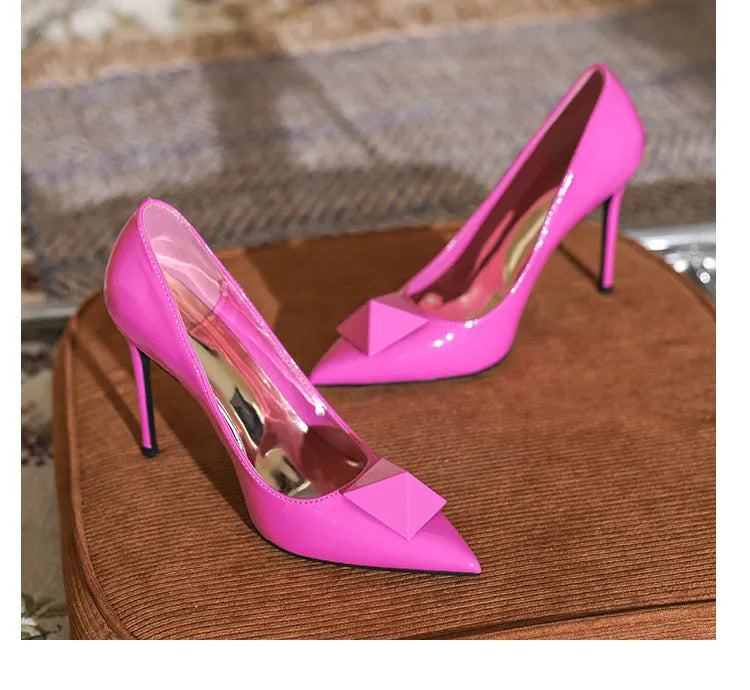 Women's pink patent leather pointed toe stiletto high heels with a buckle.