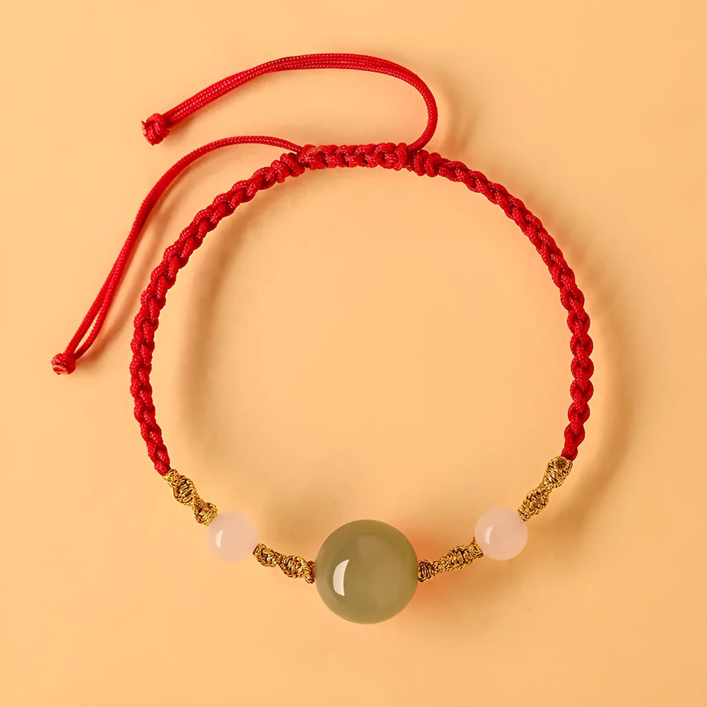Hand-woven red rope bracelet with Hetian jade beads and a detailed zodiac charm pendant.