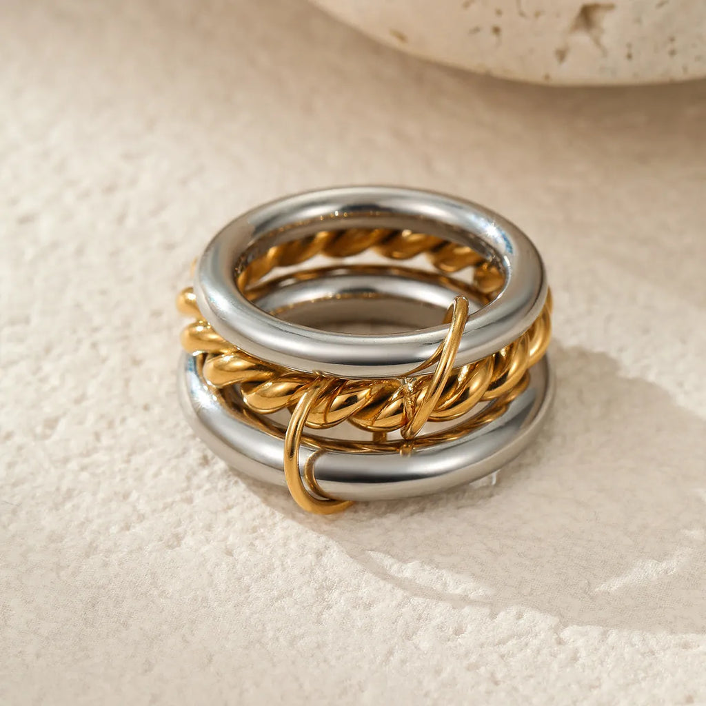 Stacked colour matching stainless steel ring with gold plating and exaggerated design on a woman's hand.