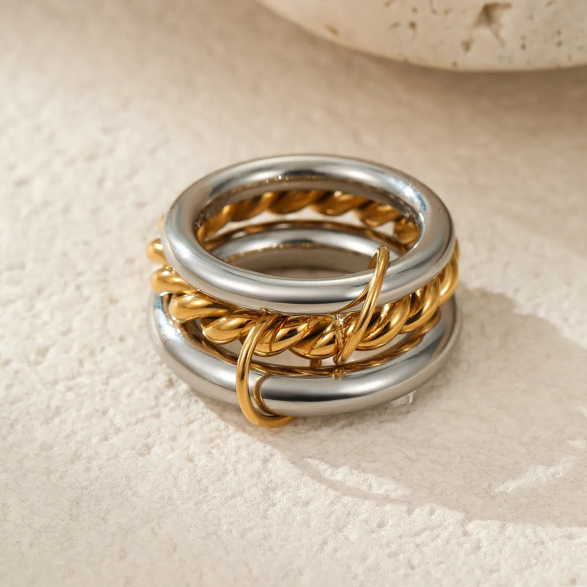 Stacked colour matching stainless steel ring with gold plating and exaggerated design on a woman's hand.