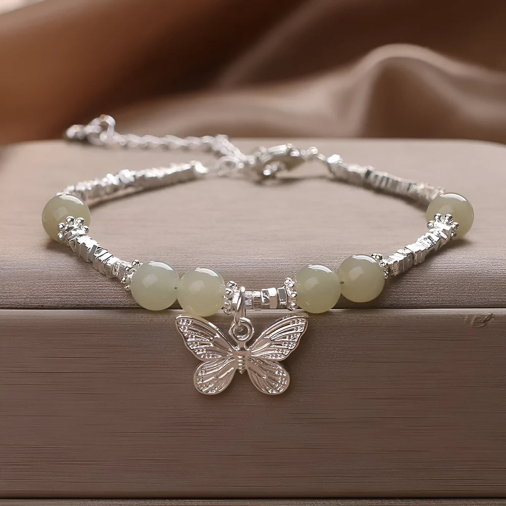 Hetian jade beads bracelet with silver butterfly pendant on a white background