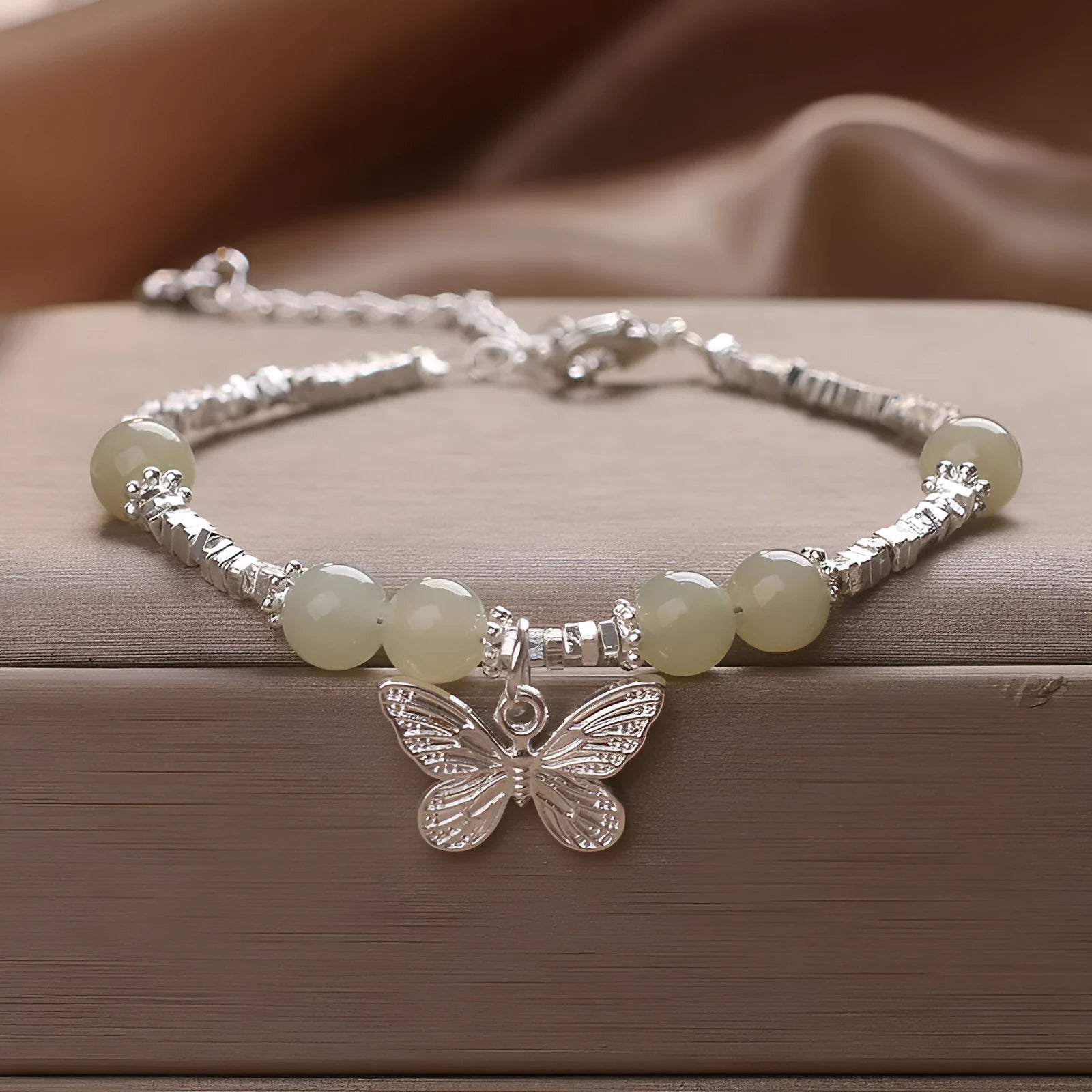 Hetian jade beads bracelet with silver butterfly pendant on a white background
