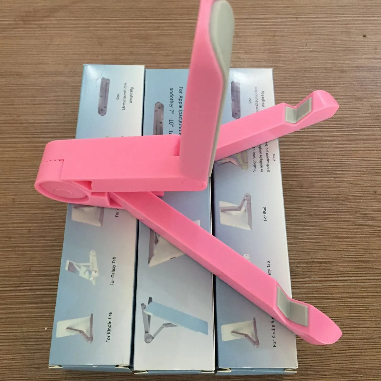 Black foldable tablet holder showing folded size next to tablet for scale