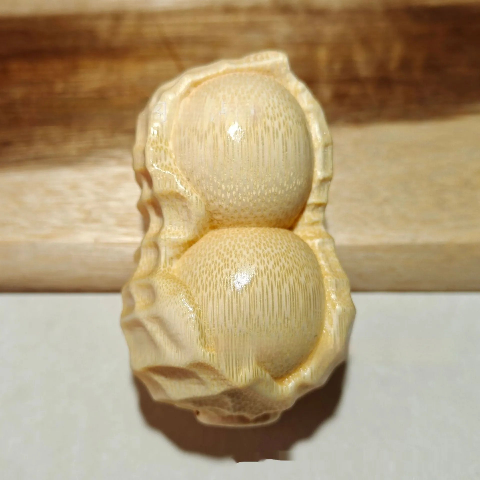 Solid natural bamboo carving of a peanut ornament on a wooden surface