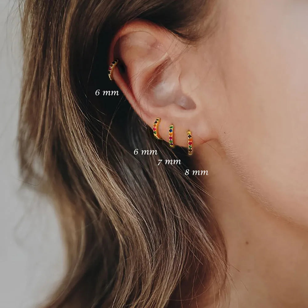 Set of three pairs of perforated circle stud earrings in gold, rose gold, and silver colours on a plain background.
