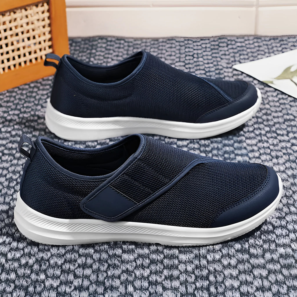 A pair of grey mesh walking shoes with a Velcro strap closure, shown on a white background.
