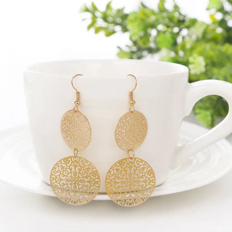 Women's round hollow gold drop earrings with dangle design on a light background