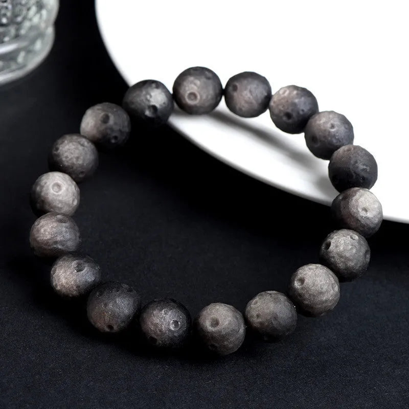 Natural obsidian crater ball bracelet with textured beads in gold or silver stone finish on a wrist.