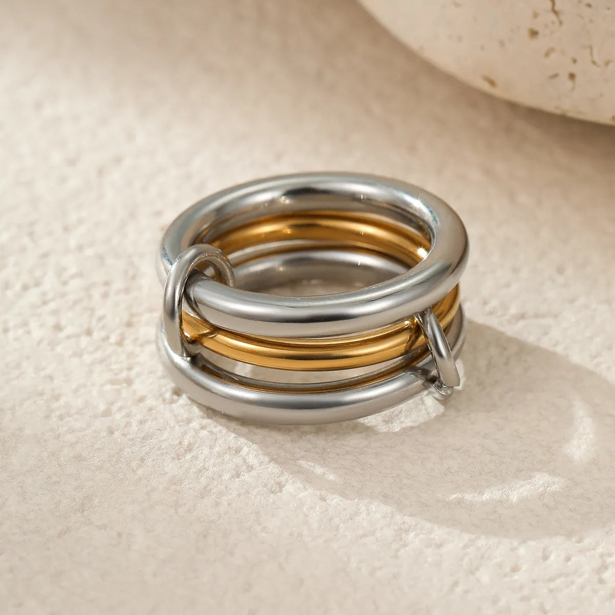 Stacked colour matching stainless steel ring with gold plating and exaggerated design on a woman's hand.