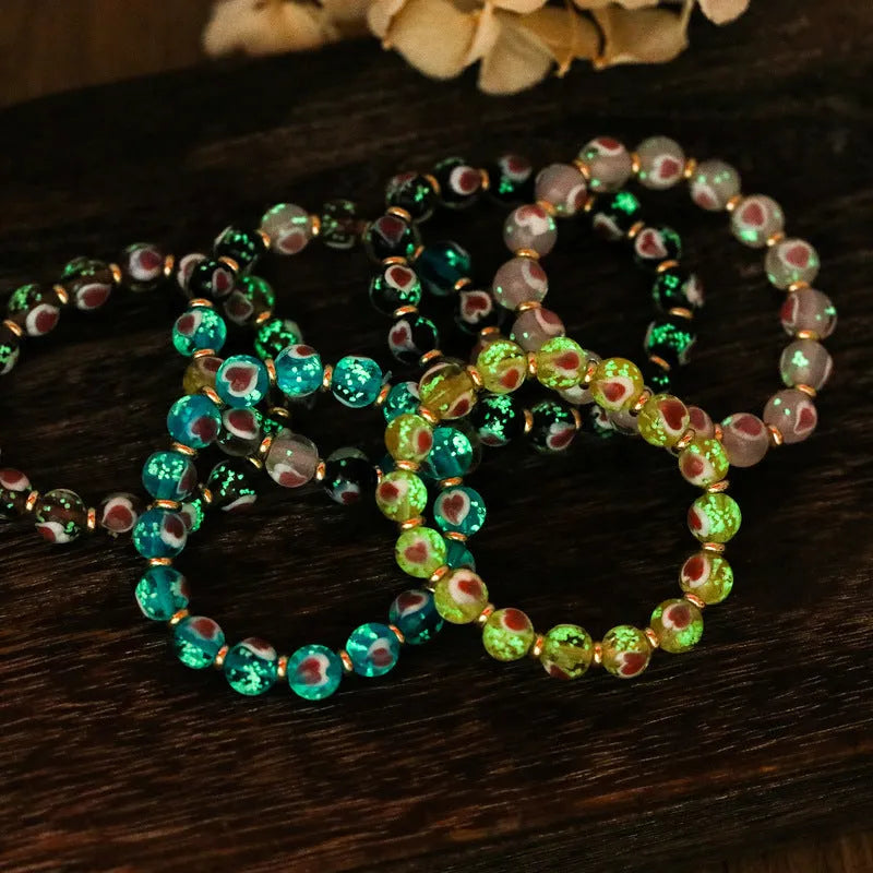 Glass bracelet with 10mm heart beads featuring ancient swallowing gold beast design in multiple colours
