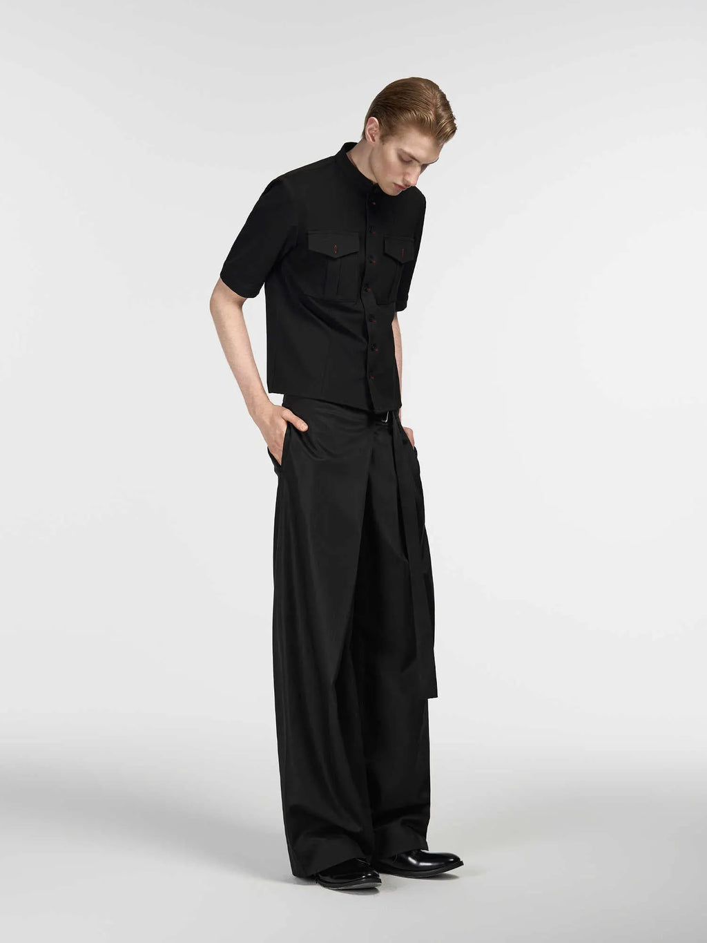 Black straight leg trousers with a single front pleat and an adjustable waistband on a hanger.