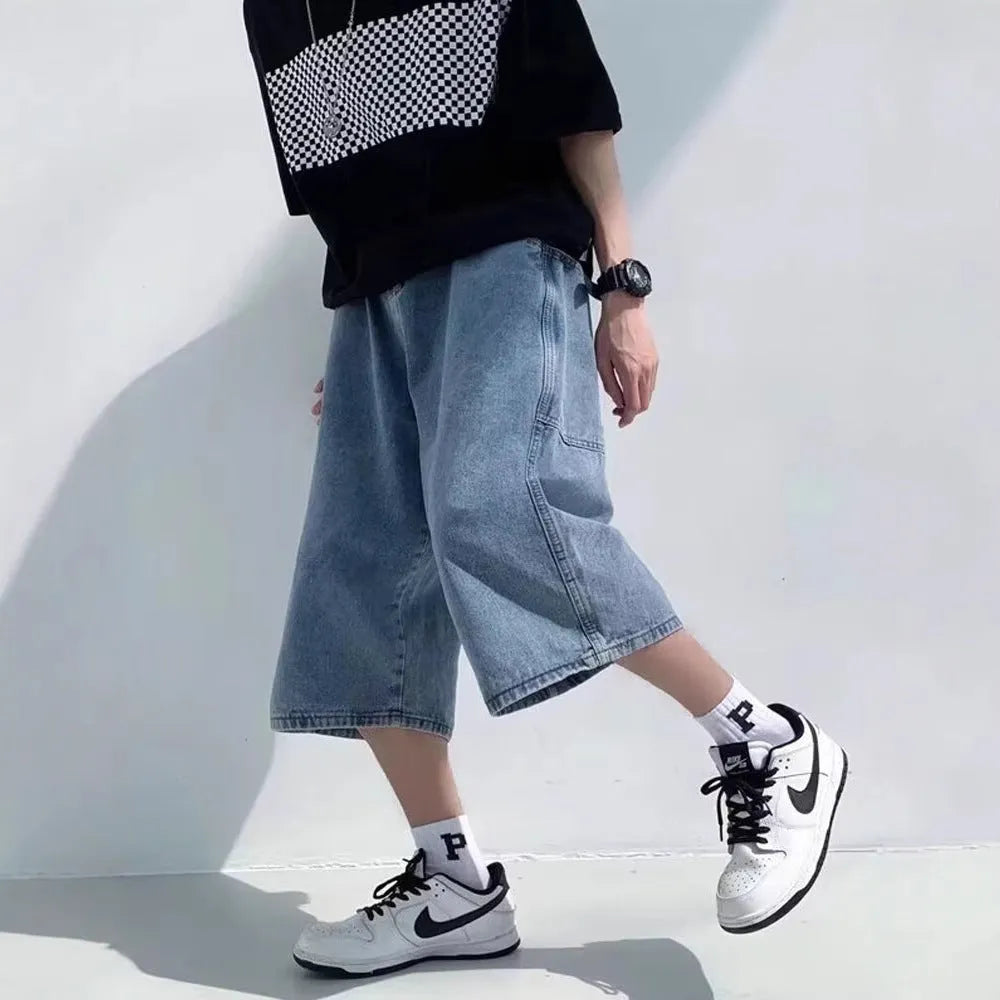 Men's blue washed denim cropped shorts with a high waist and zipper fly on a neutral background