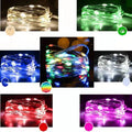 Copper wire LED string light wrapped around a tree branch, showing multiple coloured bulbs.