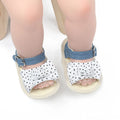 White and black Velcro baby shoes for toddlers, showing low-cut design and strap detail.