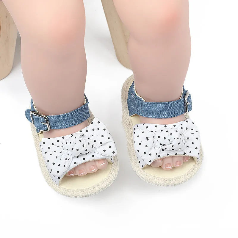 White and black Velcro baby shoes for toddlers, showing low-cut design and strap detail.