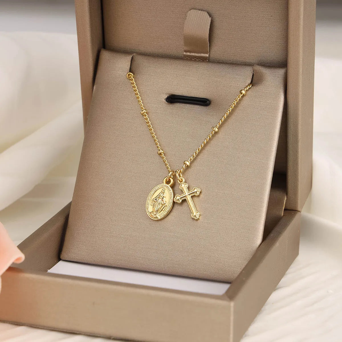 Gold coloured geometric cross necklace with a Virgin Mary ornament on a chain.