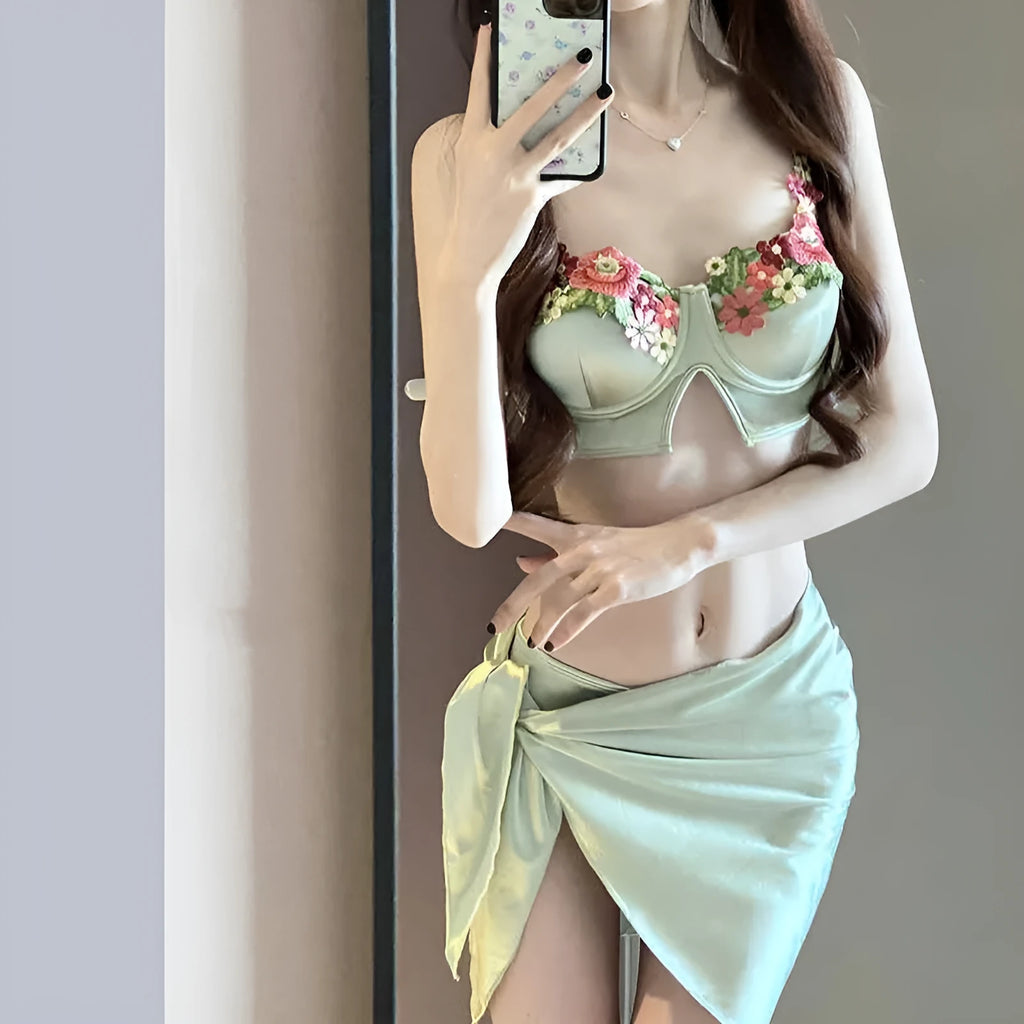 Green women's three-piece bikini set with triangle top, briefs, and skirt on white background