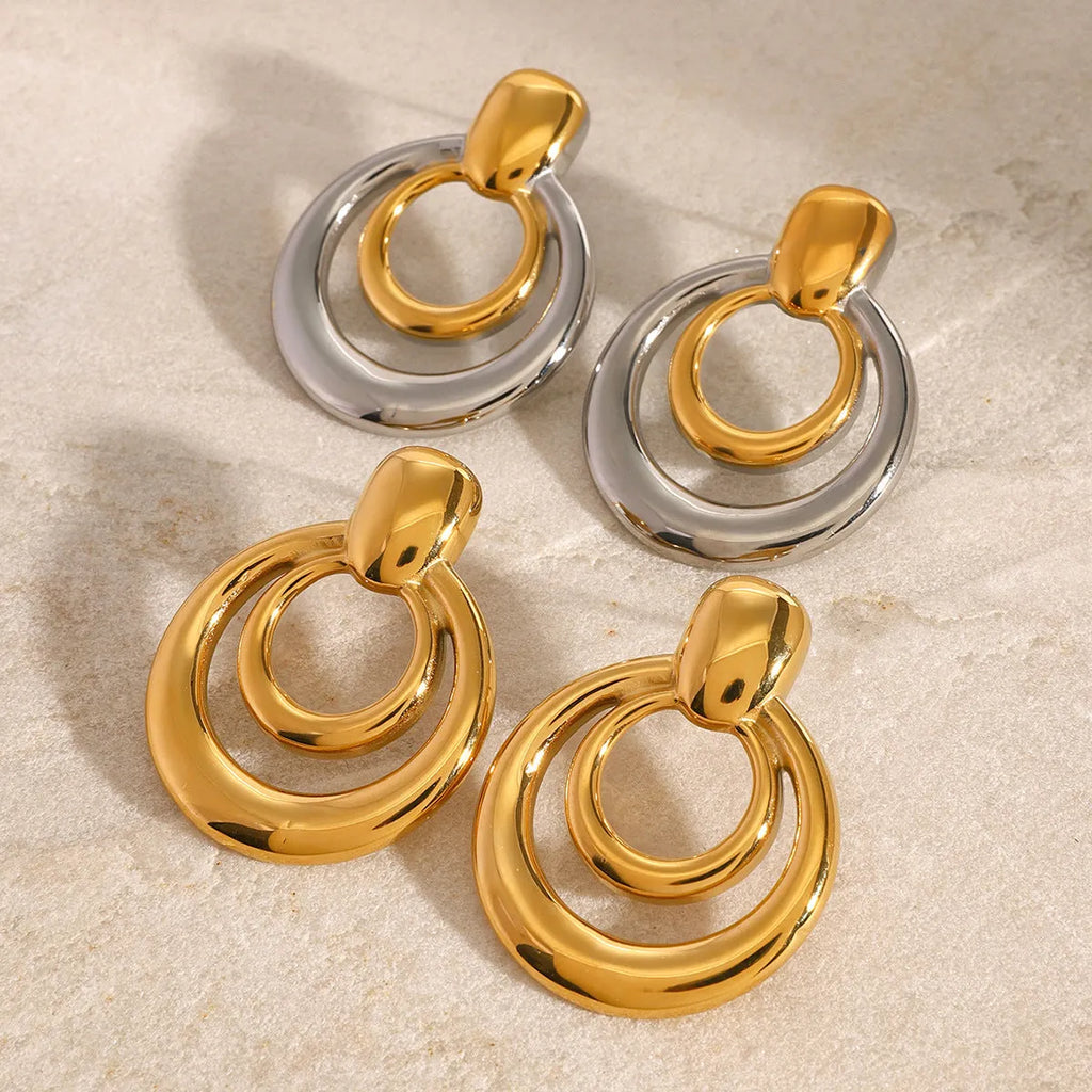 Golden round geometric stud earrings with hollow double layer design on white background