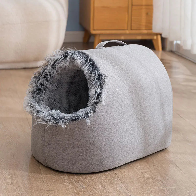Grey fleece-lined closed cat sleeping bag with portable handle on brown floor