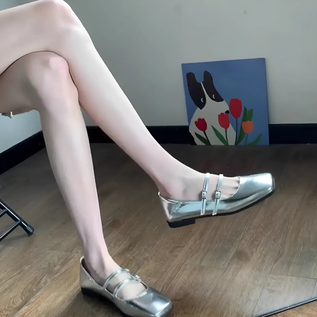 Women's silver leather Mary Jane flats with a cross-buckle ankle strap and round toe.