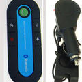 Black car Bluetooth handsfree kit clipped to a sun visor, showing the speaker grille and included car charger.
