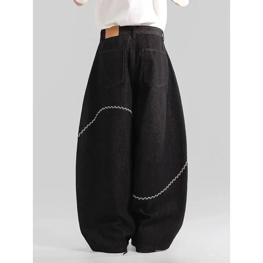 Black straight-leg denim trousers laid flat, showing zip fly and mid-waist design.