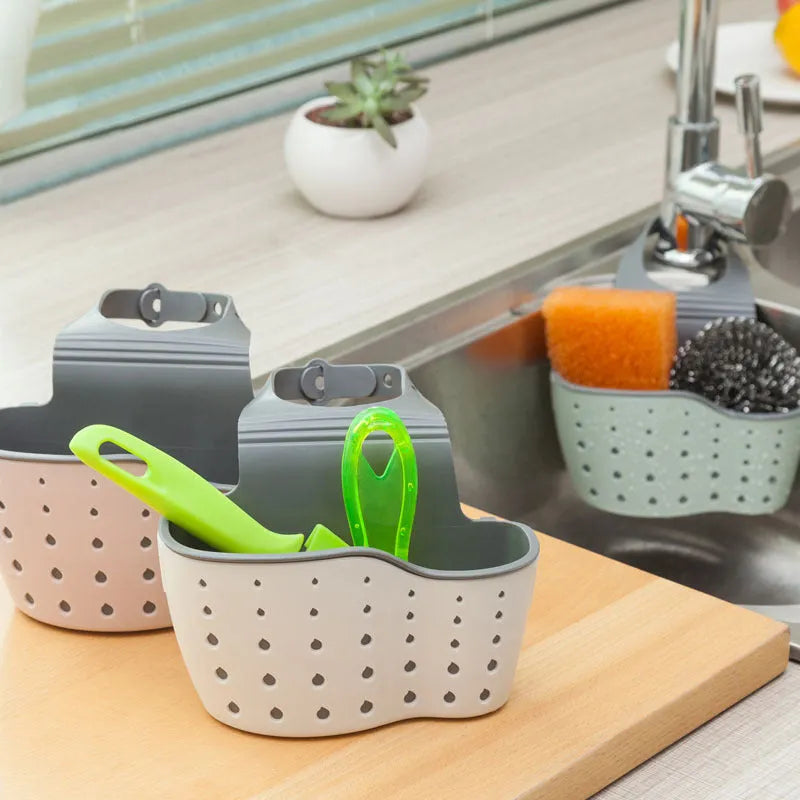 Three plastic kitchen sink storage racks in beige light blue and light pink on a draining board