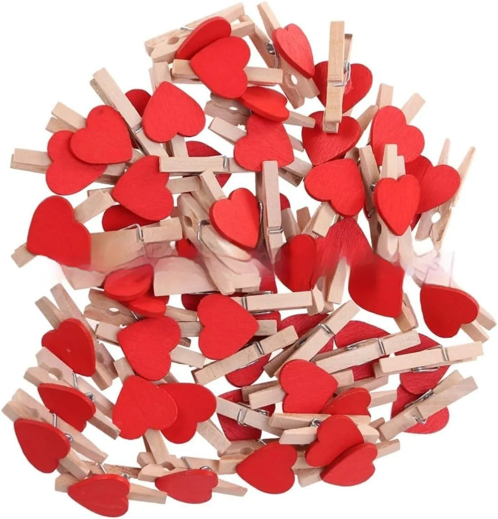 Five small wooden heart-shaped clips in red, pink, yellow, white, and rose red colours on a neutral background.