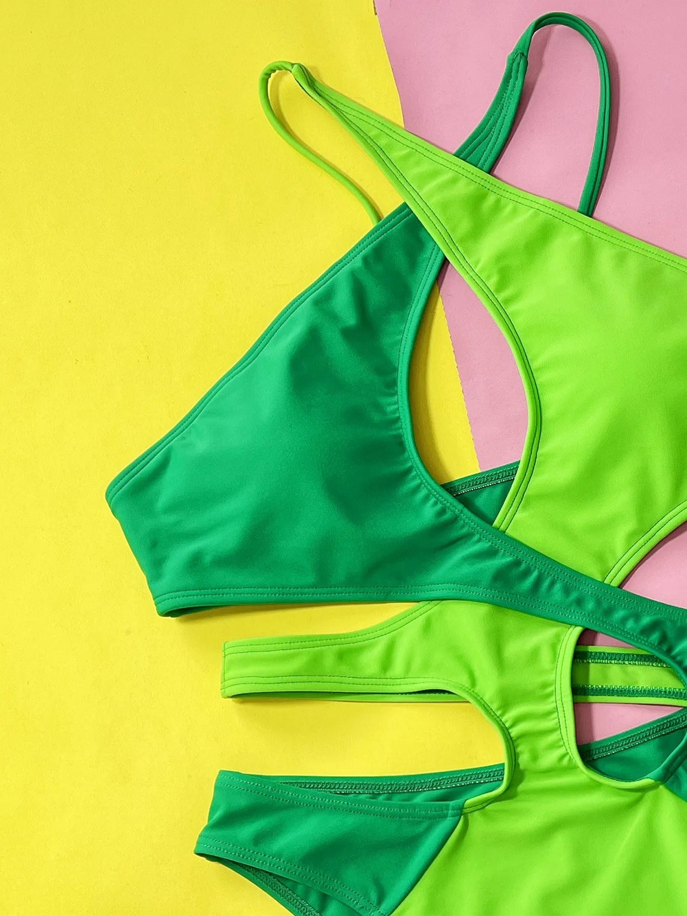 Green women's one-piece swimsuit with hollow contrast detail on a mannequin.