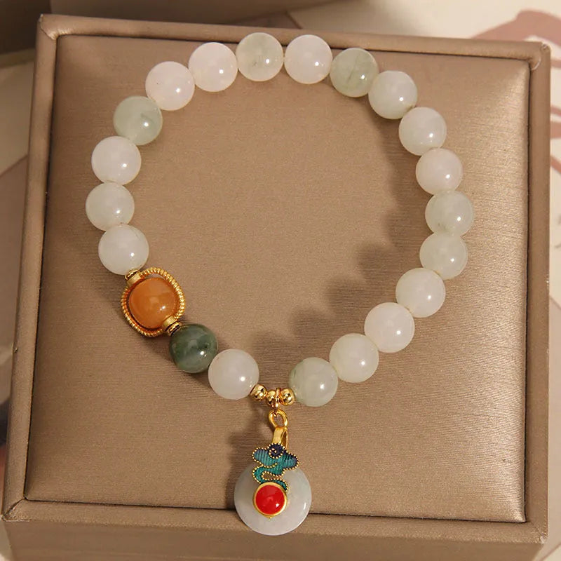 Close-up of a women's ice jade bracelet with carved Xiangyun design, pearl accents, and a jade sliding buckle.