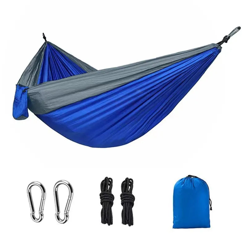 Blue nylon parachute cloth camping hammock hanging between two trees