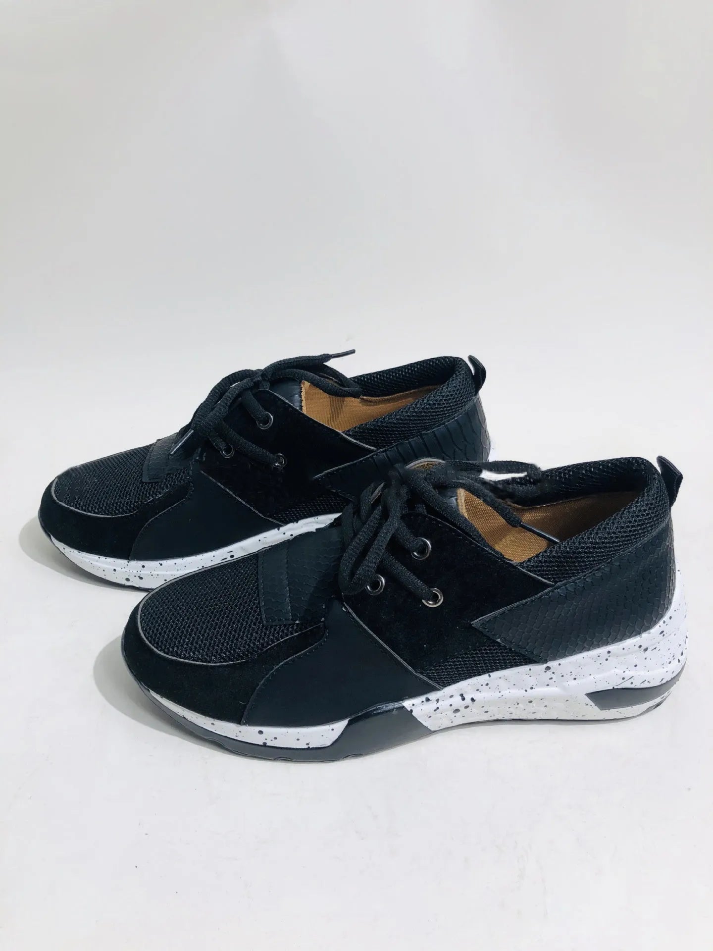 Women's black suede casual sneakers with a wedge heel on a wooden floor.
