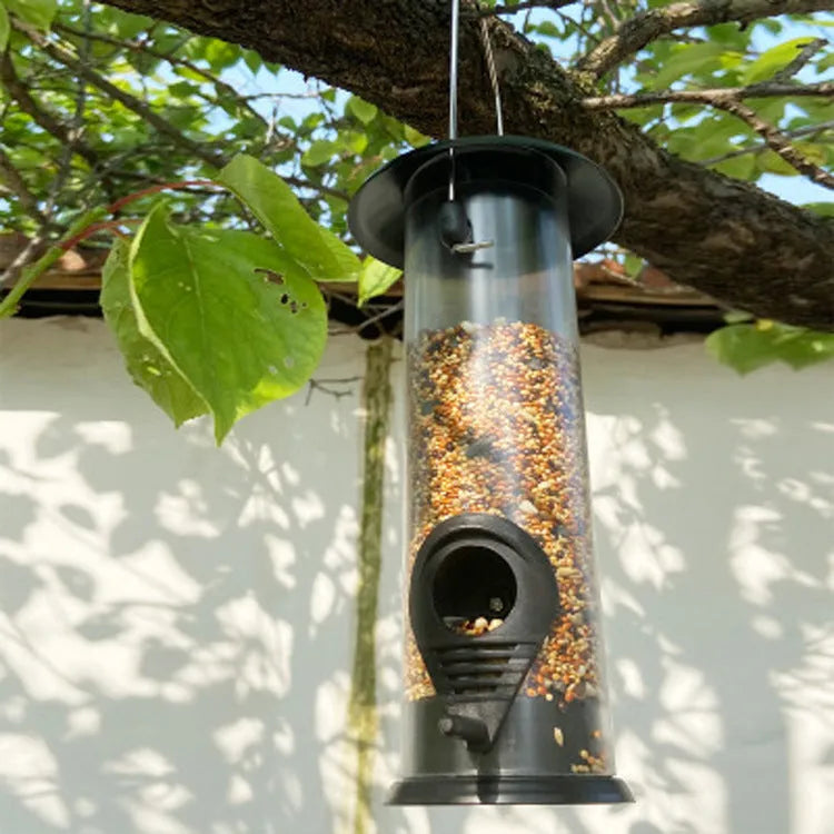 Black hanging bird feeder with transparent case, metal top and bottom, side feeding holes, and top hanging ring, 21.5x11x13cm