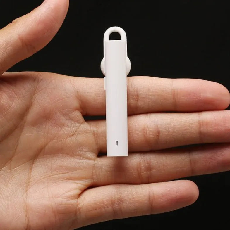 Compact black and white wireless Bluetooth headset showing size scale.
