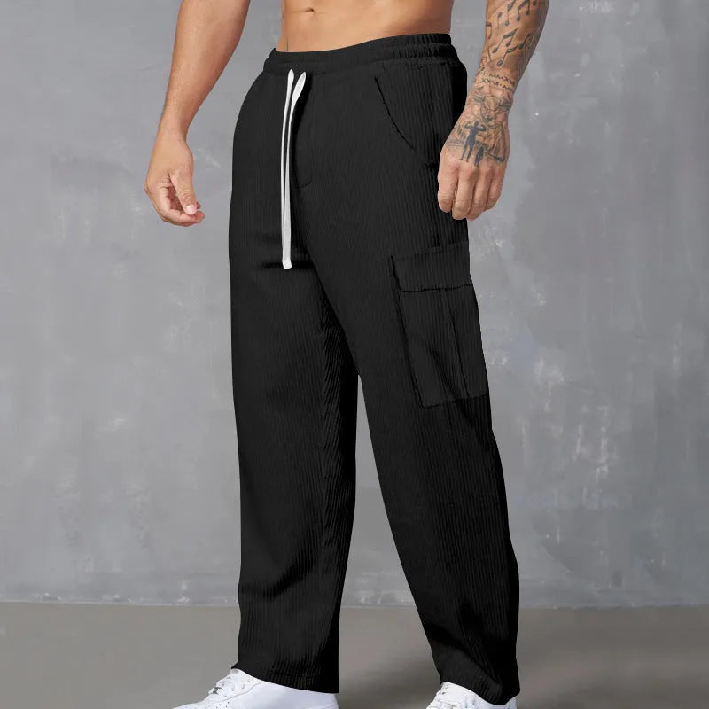 Men's navy blue corduroy wide-leg cargo trousers with a drawstring waist on a neutral background.