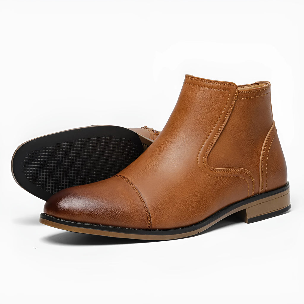 Men's black Chelsea boots with a side zipper, round toe, and low heel on a wooden sole.