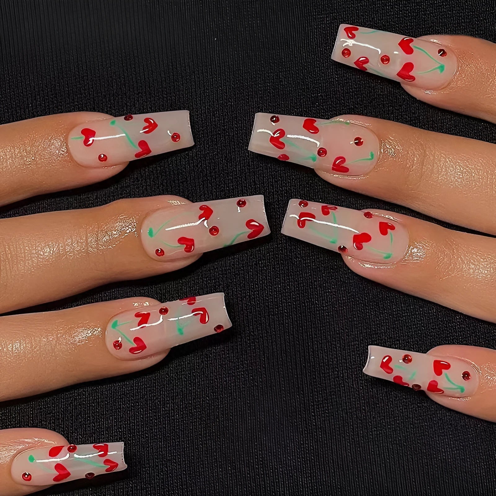 Red diamond and small cherry pattern nail art stickers on a sheet, with a tube of glue.