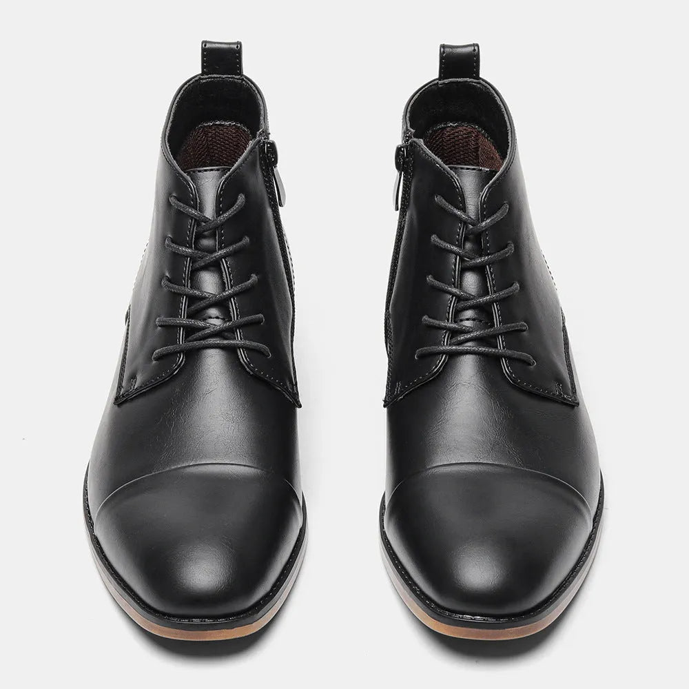 Men's black Chelsea boots with a side zipper, round toe, and low heel on a wooden sole.