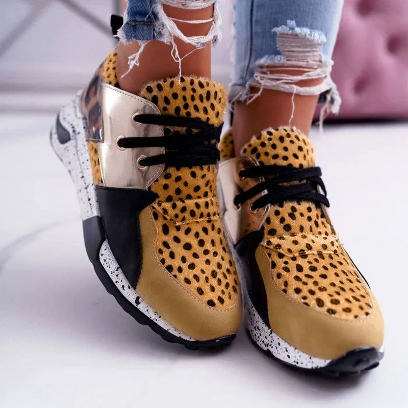 Women's black suede casual sneakers with a wedge heel on a wooden floor.