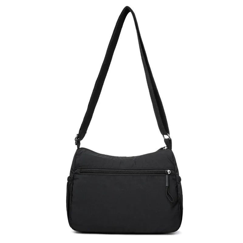 Grey water-repellent nylon crossbody bag showing front three-dimensional pocket and adjustable shoulder strap.