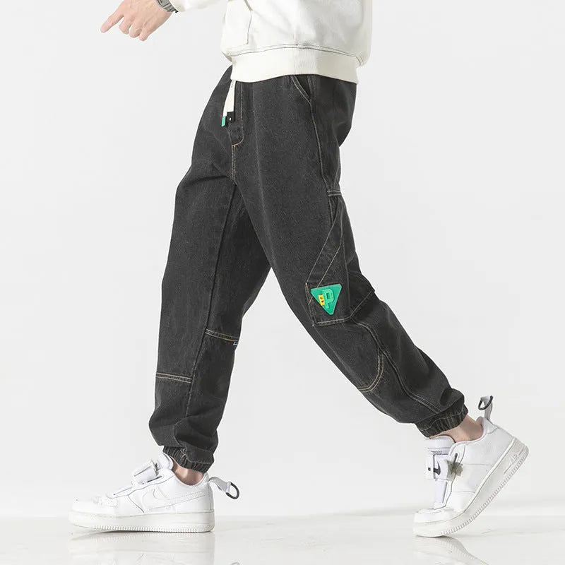 Men's black cotton loose-fit tapered trousers with a mid waist on a hanger.