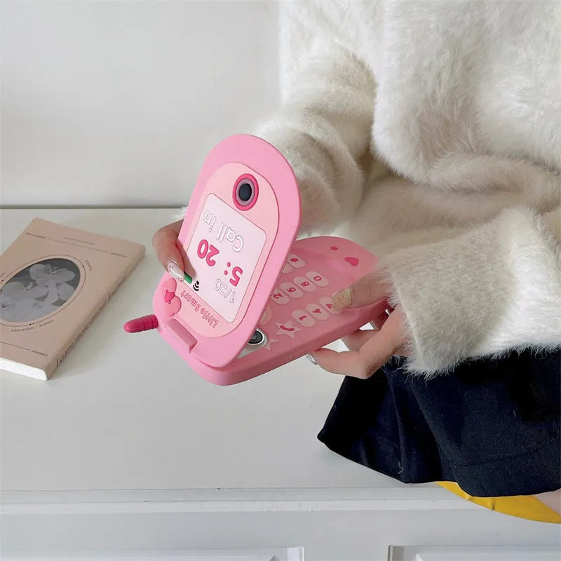 A light pink silicone iPhone case shaped like a flip phone with a built-in mirror on the front.