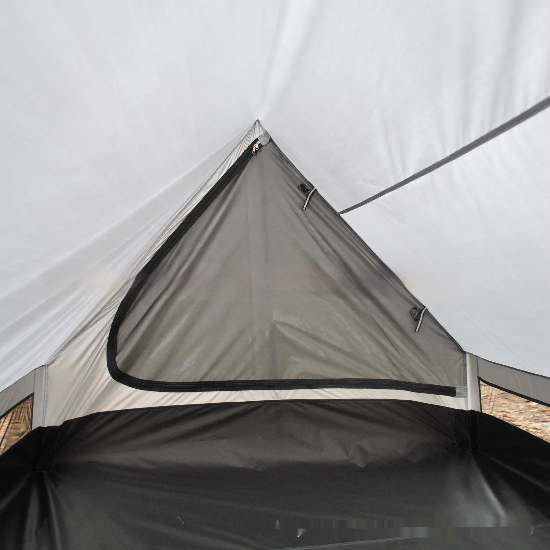 Brown ultralight A-frame hiking tent pitched with hiking poles in an outdoor setting