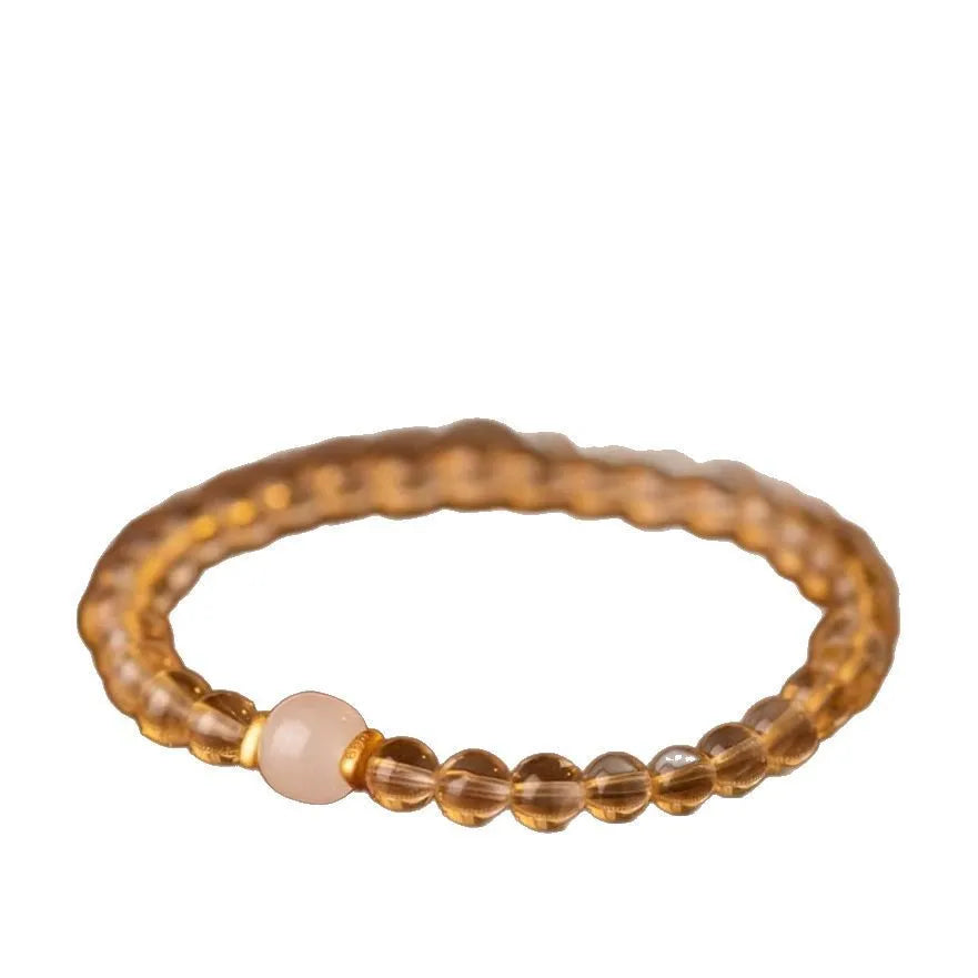 Handmade natural rutilated quartz bracelet with golden needles on wrist, showing 8mm beads.