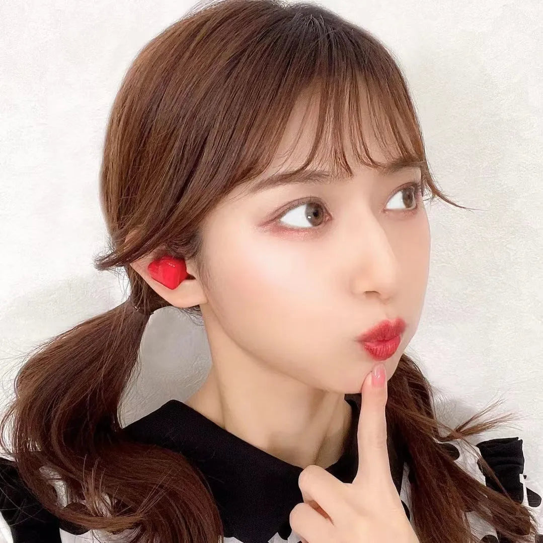 Heart-shaped wireless Bluetooth headphones in red or pink with in-ear design and charging cable