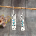 Silver geometric earrings with turquoise detail on white background