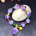 Women's amethyst bead bracelet with a Chinese fu character charm on a white background.