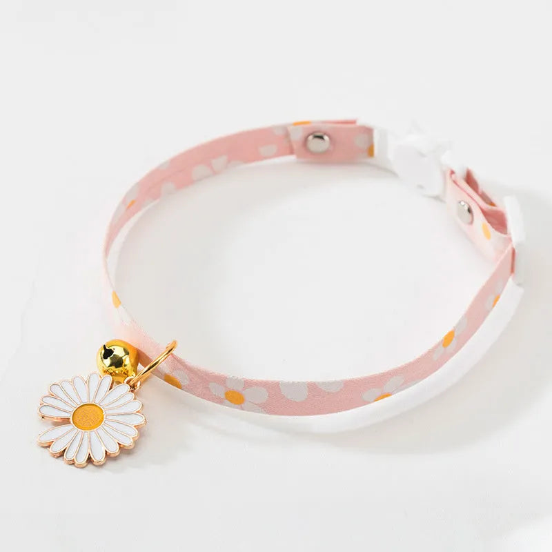 Adjustable green cat collar with a silver bell and pink bow tie on a white background.