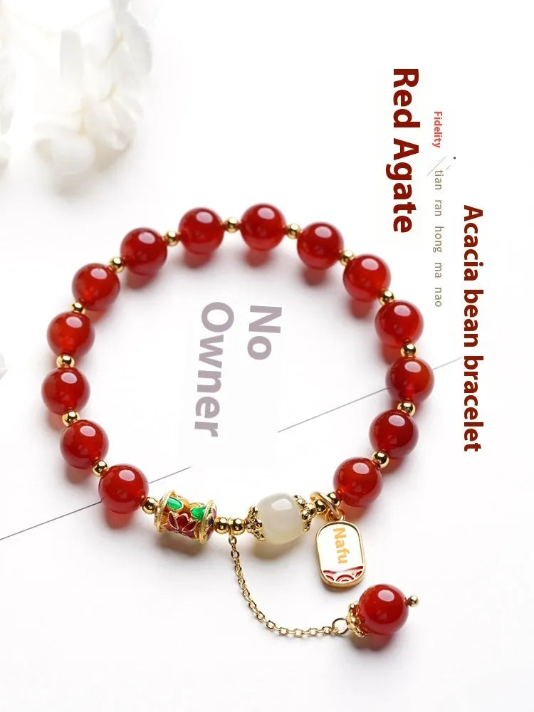 A women's bracelet with red agate beads and gold-plated metal elements on a wrist.